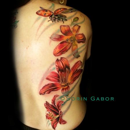 Sorin Gabor - Realistic color feminine tattoo of lillies and flying ladybug